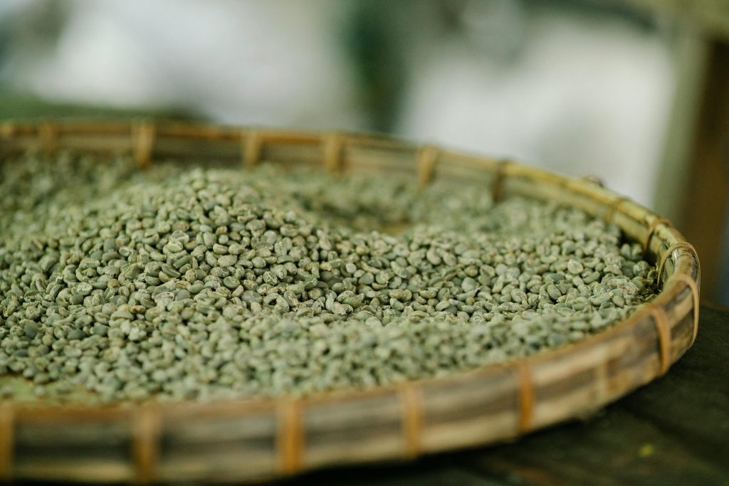 Detailed view of raw coffee beans on a bamboo tray, highlighting natural texture.